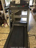 Full view of treadmill from front showing gray steel frame, black belt and handrails