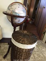 Full view of globe on stand next to wicker laundry basket, showing size and condition