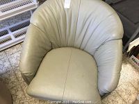 Front-on view of chair showing curved back, seat cushion, and armrests.