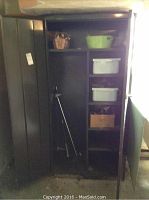 Photo of tall black metal cabinet with open doors showing contents inside including shelves with bins, a green basin, and a basket.