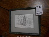 Framed ink drawing showing detailed gate with stone pillars, gray matting and marbled frame on wooden surface.