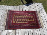 Full view of prayer rug laid flat outdoors on wooden deck