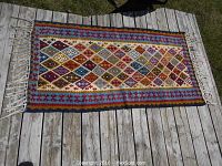 Full view of rectangular rug laid flat on wooden deck