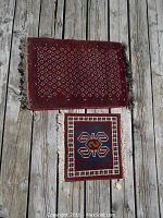 Top view of two rugs on wooden surface showing relative size and pattern.