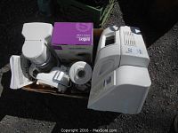 Photo showing West Bend bread maker alongside coffee maker box and blender parts in a cardboard box on pavement.