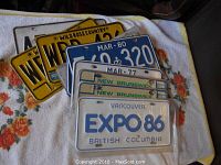 Various license plates arranged on a blanket showing some rust and wear.