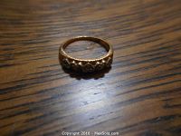 Close-up image of the ladies gold ring showing five heart-shaped details along the band on a wood surface.