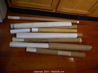Rolled vintage maps and posters on the floor beneath kitchen cabinets, showing tubes of varying sizes containing the maps/posters.
