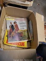 Box containing various vintage magazines and newspapers with visible colorful covers featuring mid-20th century people and barbecue theme.