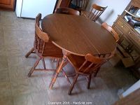 Oval wooden dining table with six matching chairs around it, showing overall furniture.