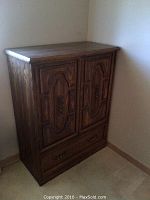 Front view of a cedar lined chest with two carved wooden doors and a drawer below.