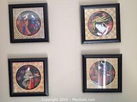 Four Asian styled framed prints on a wall with black square frames and circular art depicting traditional figures and floral patterns.