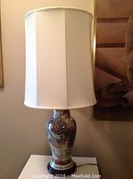 Full view of the Japanese Satsuma vase table lamp with white fabric lampshade on top showing overall height and profile.