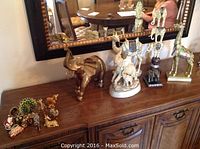 Wide shot of all figurines and trinket boxes arranged on wooden sideboard beneath mirror