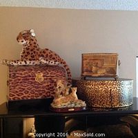Photo of entire lot showing stuffed cheetah, cheetah print chest, metal container, hat boxes, and cheetah sculptures.