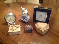 Photo showing the full collection: blue clown music box, two clocks, and four jewelry boxes of various shapes and materials on a wooden table.