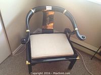 Front-facing view of the black lacquer wooden chair with brass accents and light beige upholstered seat.