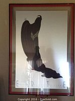 Framed Erte print with stylized figure in dark silhouette floating within frame under glass.