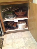 Contents of cupboard showing pots, pans, bowls, baking dishes, and casserole dish.