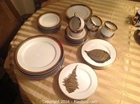 Overall view of the china set laid out on a table, showing stacks of plates and mugs.