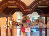 Wide view of the glass shelf displaying assorted collectible glass and china items.