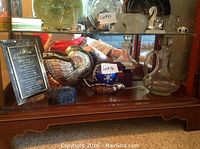 Shelf view showing silver plated nautilus shell dish, blue porcelain bowl on footed dish, clear glass decanters, glass trinket box and silver tone picture frame