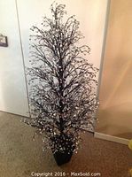 Full view of the decorative Christmas tree with mirrored branches and black base placed on carpeted floor near wall.