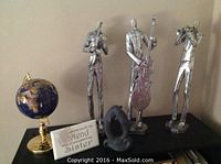 Full set displayed: three silver jazz player statues on a shelf along with 12-inch porcelain globe and two other decorative items.