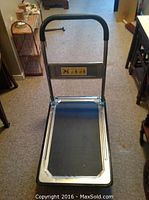 Front view of the metal folding handle moving dolly showing the platform and handle with padded grip.