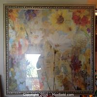 Full view of a flowered print with an ornate gold frame hanging on a wall. The print features soft, abstract flowers in colors such as orange, yellow, purple, and white.