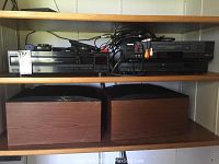 Full shelf view showing Sony 5-disc CD player, Toshiba VCR, Toshiba DVD player on upper shelf, and pair of wooden speakers on lower shelf.