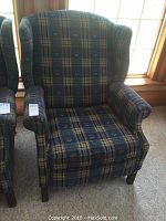 Two identical wingback recliner chairs side by side, blue plaid upholstery, wooden legs