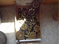 Box containing multiple brass medallions and straps with horse motifs.