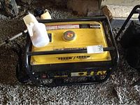 Front view of generator showing yellow top cover, black frame, two plastic oil funnels placed on top