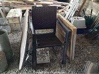 Three dark brown stacking patio chairs placed outdoors against various items