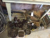 Under shelf showing coils of cable, buckets and cans filled with square nails, brown porcelain insulators scattered