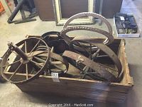 Photo showing 4 rusted metal spoked wheels, 4 decorative metal grates, and wooden box containing all items.
