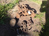 Top view of all four pulleys laid on the ground showing varying sizes, hooks, shackles and rusted metal surfaces.
