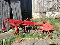 Overall view of red steel three-point hitch rotary hay rake on concrete slab