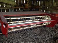 Side-angle view showing red steel housing, Hesston PT-7 logo, pickup reel tines