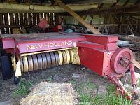 Side view of baler in barn showing pickup tines and flywheel
