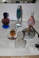 Collection of six perfume bottles in various styles showed on white cloth background, highlighting shapes and colors