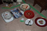 Photo showing nine plates and platters arranged on carpet including decorative plates and Asian style platter