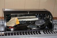 Roll top metal storage box containing the medical instruments and tools inside, shown closed