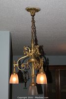 Full view of four-light chandelier suspended by chain from ceiling