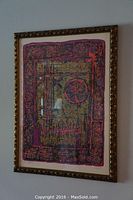 View of the framed lithograph on wall with visible abstract industrial design, vibrant colors and signature with numbering at bottom.