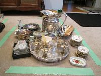 Overview of lot showing silver plate pitcher, porcelain plates in stacks, appetizer skewers on a silver tray, Lenox salt and pepper shakers, and assorted small tableware items