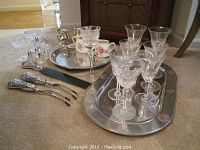 Overall view of lot including sterling silver items and glassware displayed on carpeted floor.