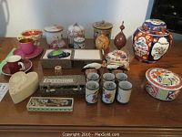 Multiple porcelain jars, cups, tumblers, trinket boxes, chef figurines, wooden box and tool displayed on table