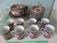 Photo showing full set of china including stacked bowls, dessert plates, two larger plates, and 8 cups with oriental floral and bird patterns.